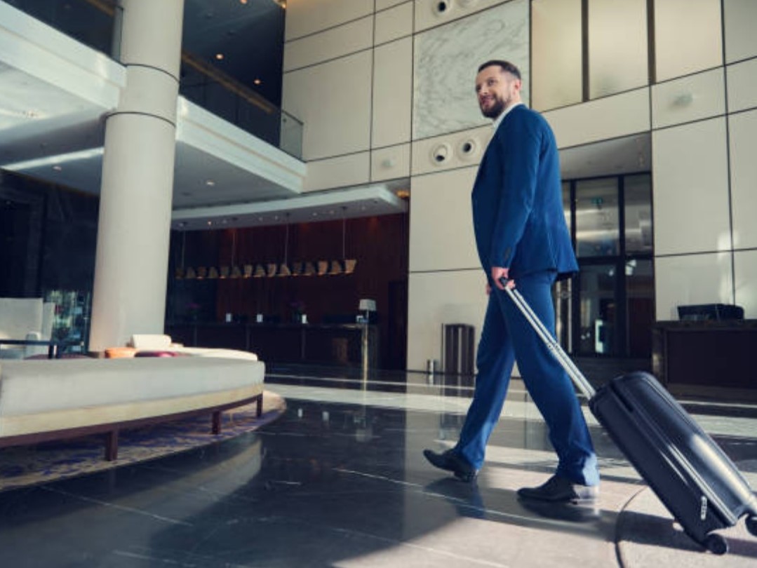 Man rolling suitcase in the hotel lobby